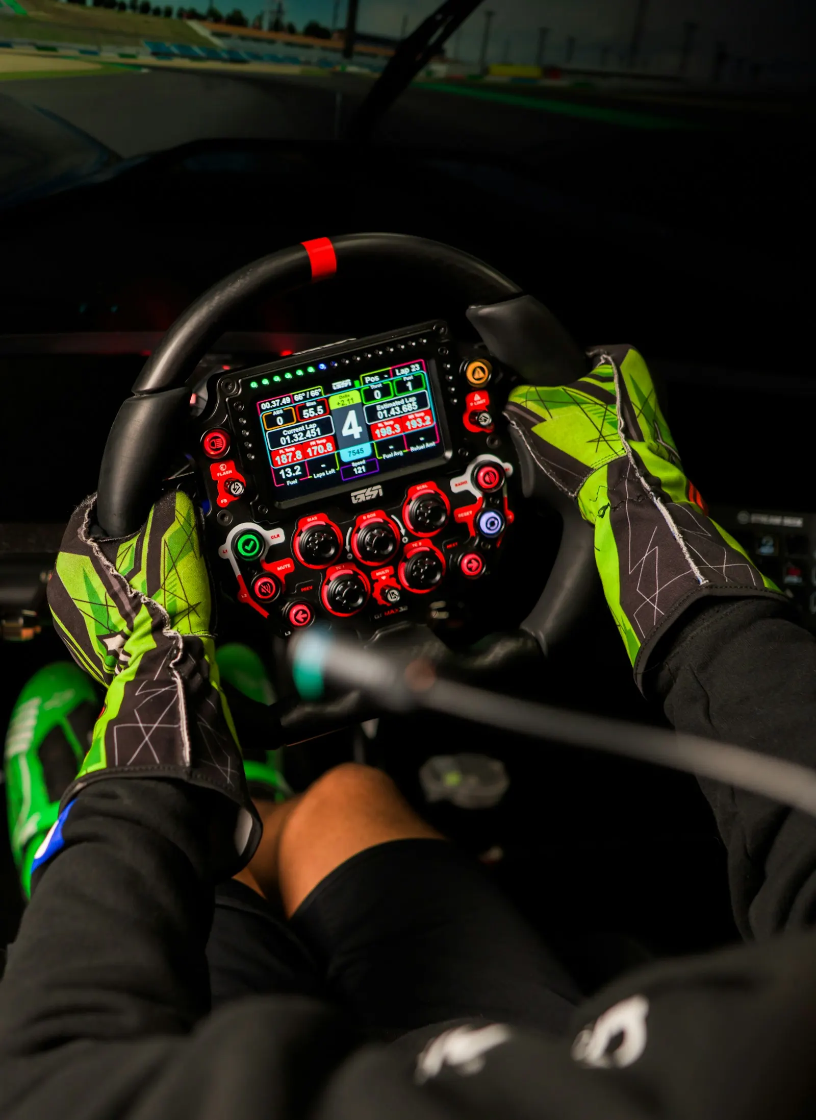 Gloved hands on a sim racing wheel with a telemetry display