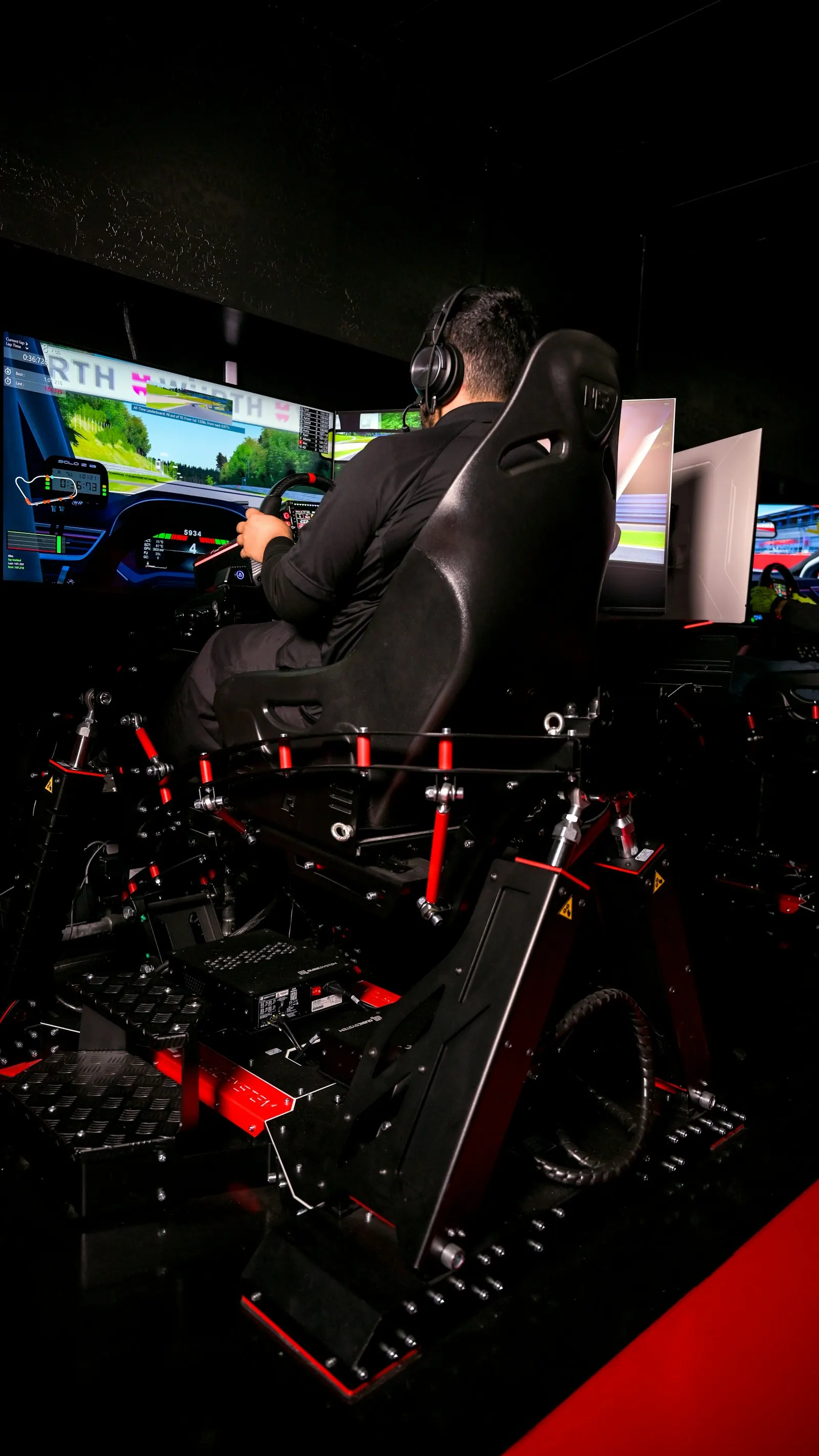 A driver in a motion rig in front of three screens